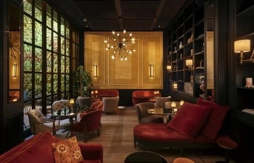 The lounge: red velvet sofas, bookshelves, a starburst chandelier and a glass wall onto the garden.